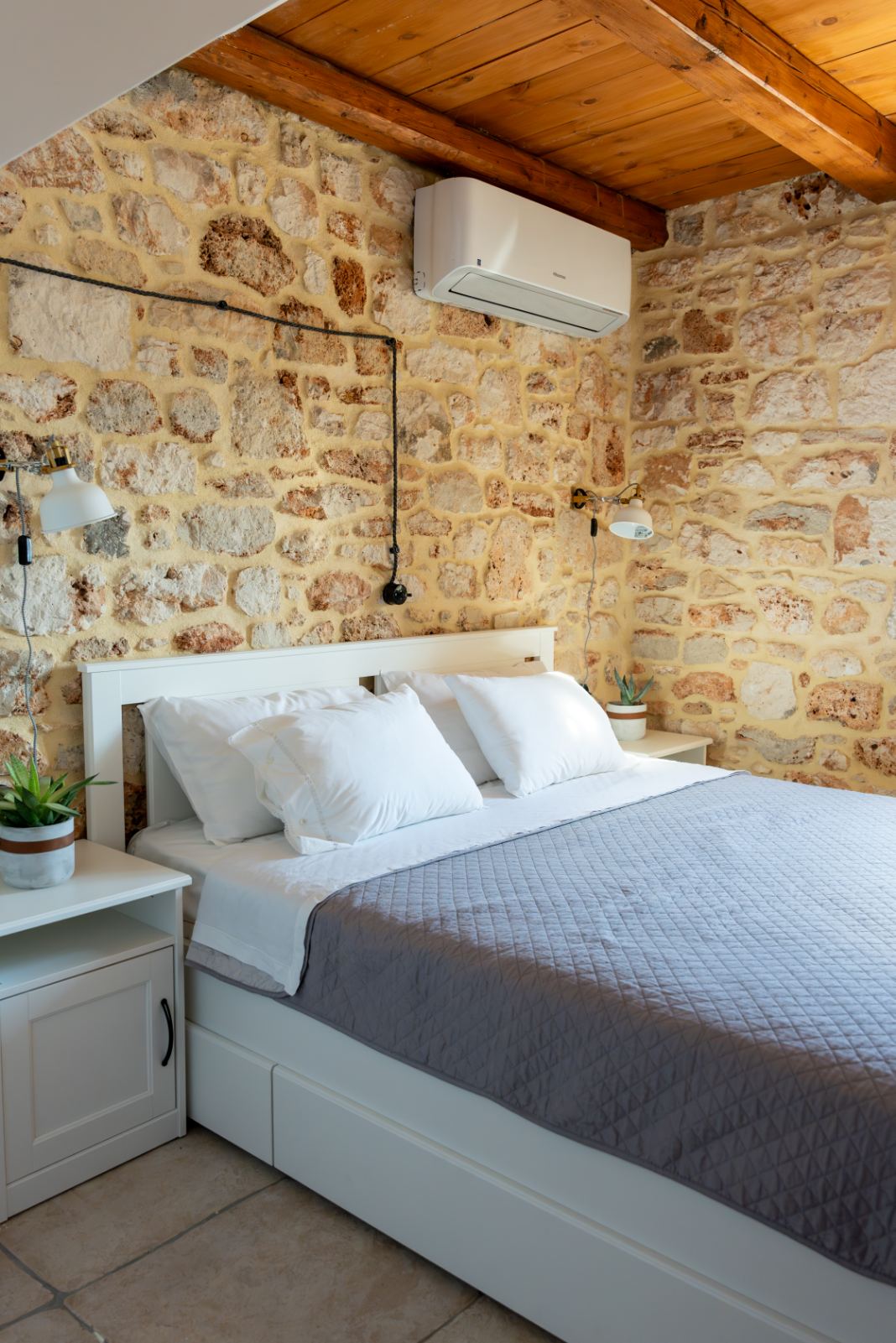 Cozy bedroom with exposed stone walls and wooden ceiling
